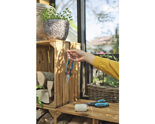 Scène de jardin avec jardinière, bûches, sécateur et une personne