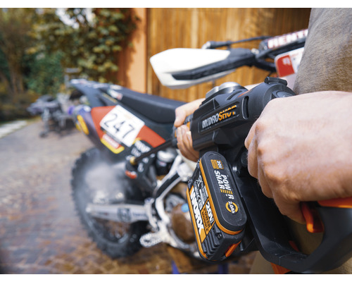 Une personne nettoie une moto avec un nettoyeur haute pression sans fil.