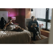 Chambre lumineuse avec des personnes, un lit, un fauteuil et la lumière du jour
