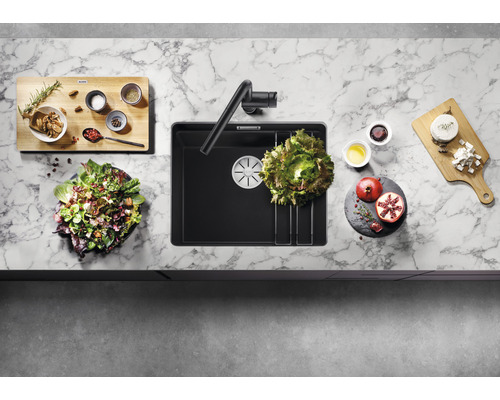 Küchenspüle mit Armatur, Schneidebrett und Zutaten auf einer Arbeitsplatte.