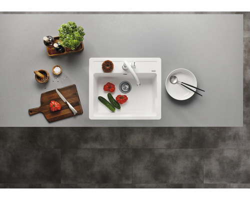Évier de cuisine avec robinet, planche à découper, vaisselle et aliments sur un plan de travail