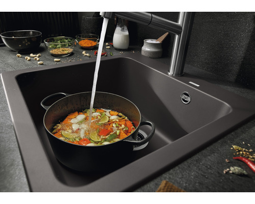 Spüle mit Wasserhahn und Topf gefüllt mit Gemüse