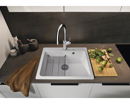 Küchenspüle mit Abtropfgitter, Armatur und diversen Küchenutensilien auf einer Arbeitsplatte