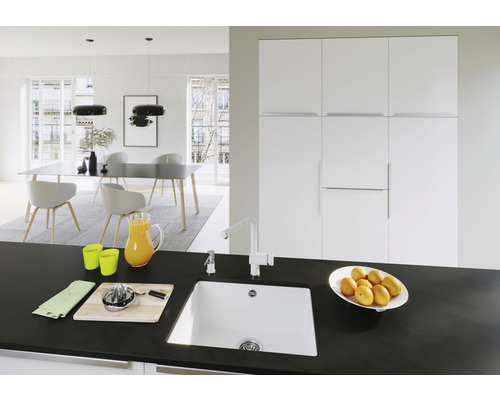 Helles Interieur mit Küchenspüle, Armatur, Arbeitsplatte und Essbereich.