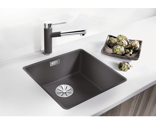 Spüle mit Wasserhahn und Artischocken auf der Küchentheke