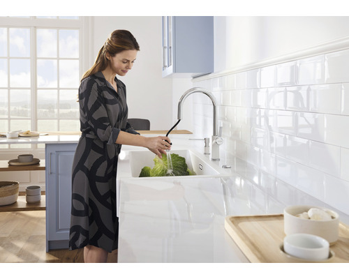 Frau wäscht Kohl in einer modernen Küche mit Spüle und Armatur.