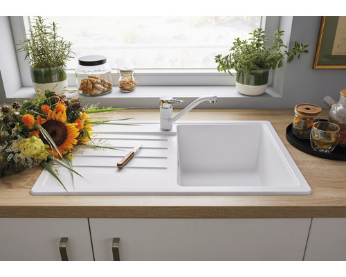 Küchenspüle mit Abtropffläche und Einhebelmischer vor einem Küchenfenster dekoriert