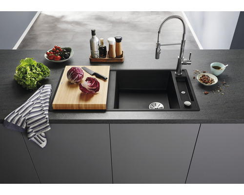 Küchenspüle mit Armatur, Schneidebrett und Lebensmitteln auf einer Küchentheke.