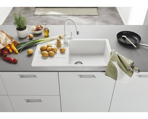 Küchenspüle mit Armatur, Gemüse und Küchenutensilien auf einer Arbeitsfläche