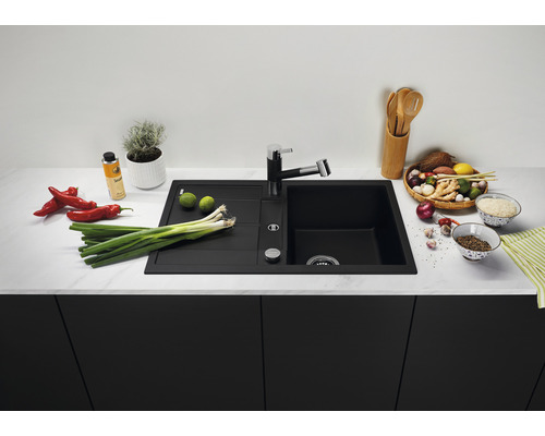 Évier de cuisine noir avec robinet sur un comptoir de cuisine avec des aliments