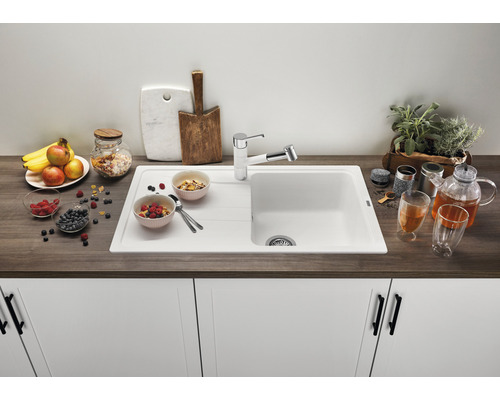 Évier de cuisine avec égouttoir, robinetterie et aliments décoratifs sur un plan de travail