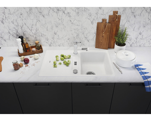 Küchenspüle mit Armatur, Gemüse und Küchenutensilien auf einer Küchentheke.