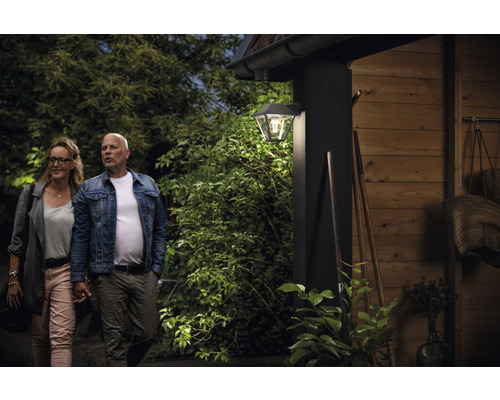 Szene mat engem Koppel virun engem Haus mat enger Baussewandlampe.