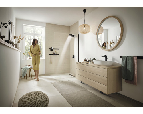 Helles Badezimmer mit Dusche, Waschtisch und rundem Spiegel