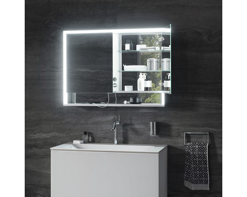 Salle de bain avec armoire de toilette éclairée, lavabo et robinet devant un mur sombre