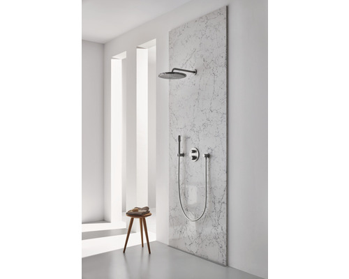 Ensemble de douche avec douche de tête, douchette à main et robinetterie sur un mur en marbre dans une salle de bain lumineuse.