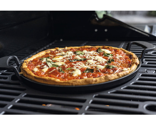 Pizza sur plaque de cuisson avec poignées sur un barbecue
