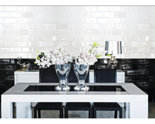 Esszimmer mit Esstisch, Stühlen, silbernen Vasen und Fliesenwand