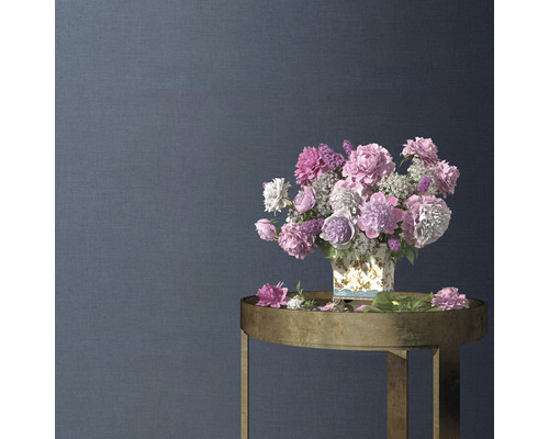 Dekoratives Blumenarrangement in einer Vase auf einem Beistelltisch vor einer strukturierten Wand