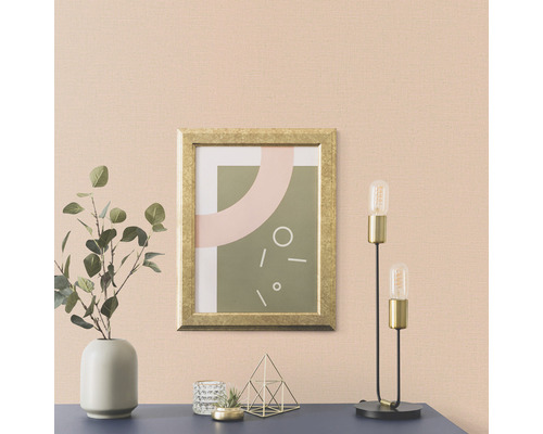 Wohnraum mit einem Bild im Goldrahmen, einer Lampe und einer Vase mit Pflanzen auf einer Kommode.