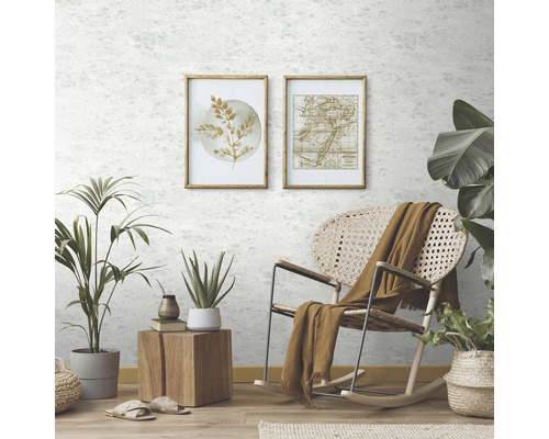 Heller Raum mit hellgrauer Mustertapete, botanischen Kunstdrucken, Rattansessel, Pflanzen und Holzelementen.