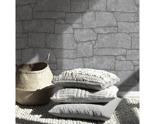 Mur à motifs de pierre, panier et coussins sur un tapis.