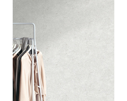 Wand mit abstrakter Musterung neben einer Kleiderstange mit Kleidungsstücken.