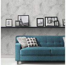 Wohnzimmer mit grauer Vliestapete, Sofa und Bilderrahmen auf einem Regal