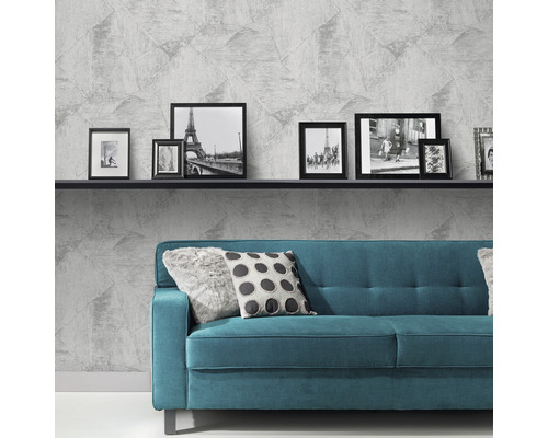 Wohnzimmer mit grauer Vliestapete, Sofa und Bilderrahmen auf einem Regal