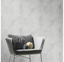 Eine helle Wand mit geometrischem Muster und ein Stuhl mit Kissen und Zierkugeln.