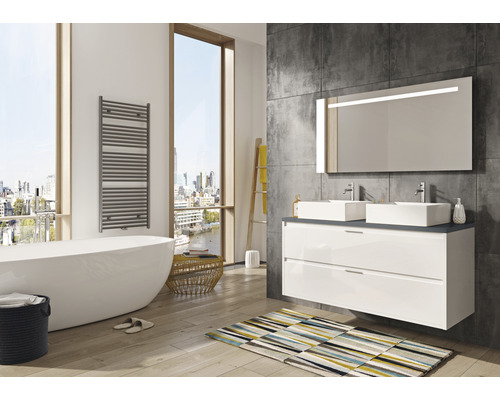 Helles Badezimmer mit Badewanne, Waschtisch mit zwei Waschbecken, beleuchtetem Spiegel und Handtuchwärmer