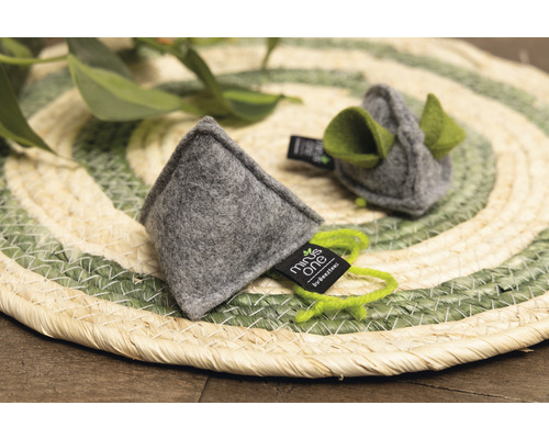 Zwei graue Katzenspielzeuge aus Filz mit grünen Details auf einem runden Untersetzer