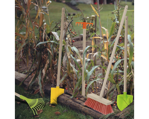 Gartenwerkzeuge wie Rechen, Schaufel und Besen im Gartenbeet