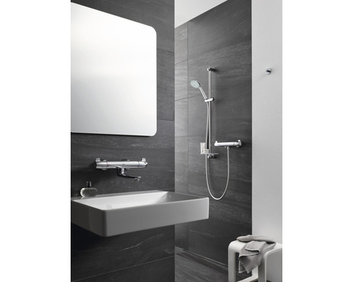 Salle de bain moderne avec miroir rectangulaire, vasque à poser, robinetterie et ensemble de douche.