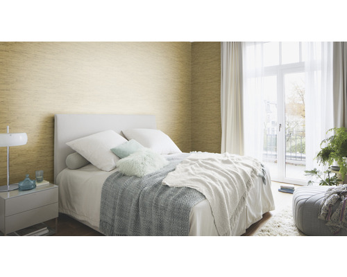 Schlafzimmer mit Bett, Nachttisch und goldfarbener Wandtapete.