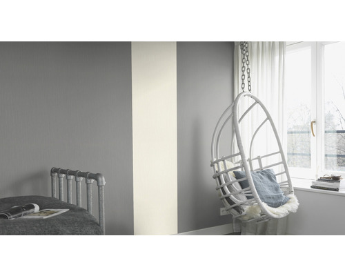 Chambre avec décoration murale en gris et blanc et fauteuil suspendu en osier