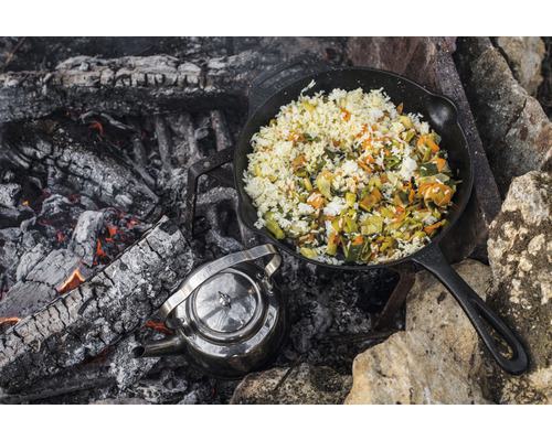 Gusseisenpfanne mit Reis und Gemüse am Lagerfeuer mit Teekessel