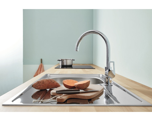Évier de cuisine avec robinet, planche à découper et patates douces sur un plan de travail