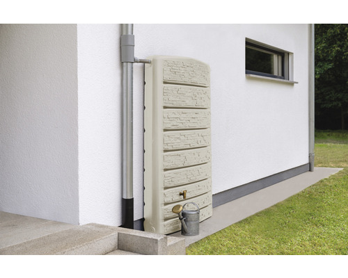 Regentonne mit Wasserhahn und Gießkanne neben einem Fallrohr an einer Hauswand