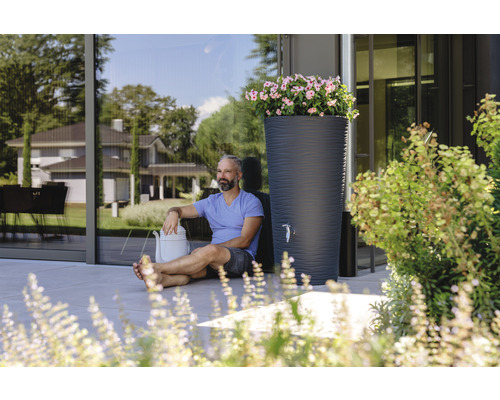 Scène avec réservoir d''eau de pluie, arrosoir et homme dans le jardin