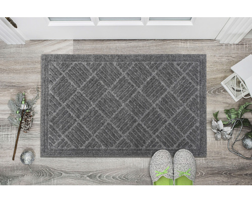Paillasson gris avec motif géométrique devant une porte