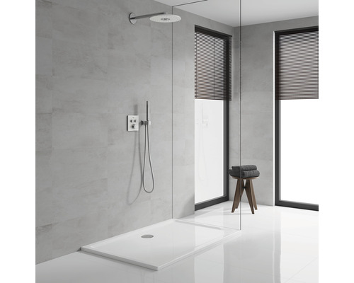 Espace douche avec receveur de douche, pomme de douche, robinetterie et tabouret avec serviettes dans une salle de bains.