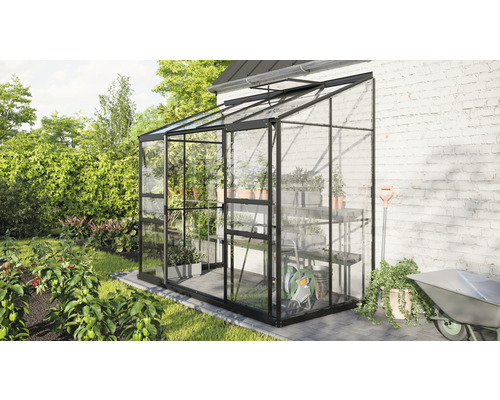 Gewächshaus aus Glas mit Regalen und Gartengeräten im Garten