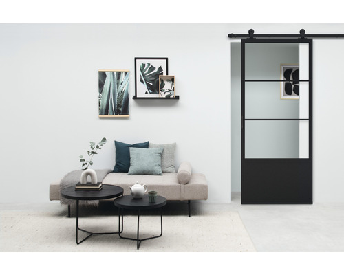 Wohnzimmer mit Sofa, runden Tischen, Wanddekorationen und Glasschiebetür