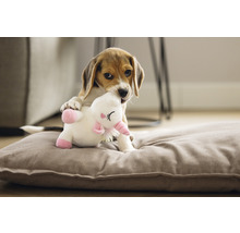 Beagle Welpe spielt mit einem Plüscheinhorn auf einem Hundekissen