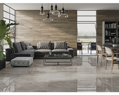 Salon avec carrelage gris au sol, mur en bois, canapé gris et table à manger avec chaises