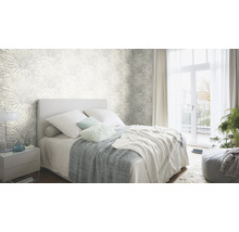 Chambre lumineuse avec papier peint à motifs, lit et table de chevet