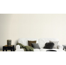 Wohnzimmer mit weißer Couch, Kissen und Beistelltisch vor einer Wand