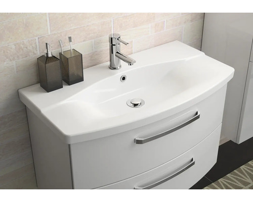 Meuble sous-lavabo avec lavabo, robinet, distributeur de savon et gobelet à brosse à dents dans la salle de bain.