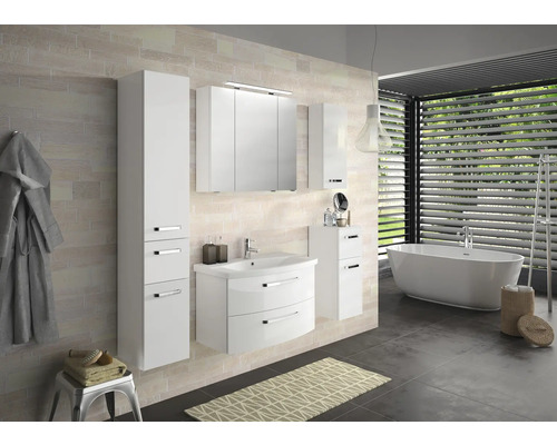 Salle de bains avec lavabo blanc, armoire de toilette et baignoire devant la fenêtre